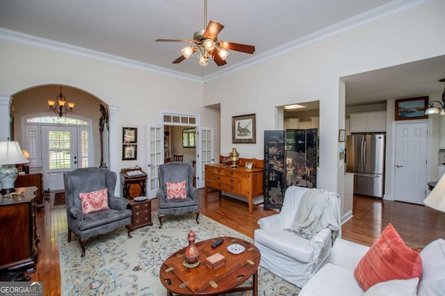 living room featuring arched walkways, ornamental molding, french doors, and wood finished floors