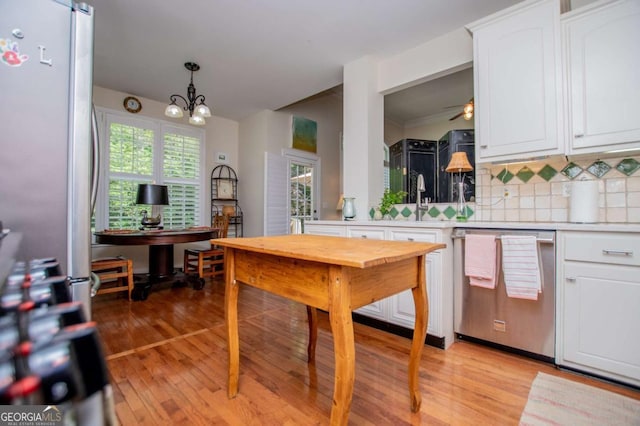 kitchen featuring white cabinets, light wood finished floors, light countertops, stainless steel appliances, and decorative backsplash