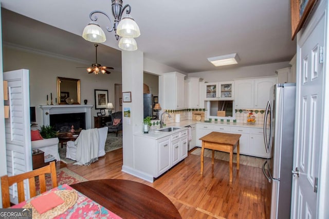 kitchen with a sink, freestanding refrigerator, open floor plan, glass insert cabinets, and light wood-style flooring