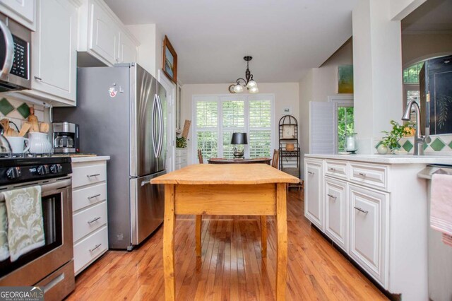 kitchen with appliances with stainless steel finishes, light wood-style floors, wood counters, a chandelier, and white cabinetry