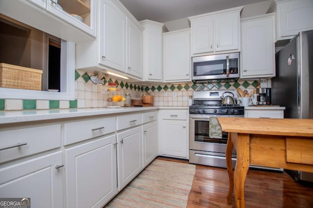 kitchen featuring light wood-style floors, decorative backsplash, white cabinetry, and stainless steel appliances