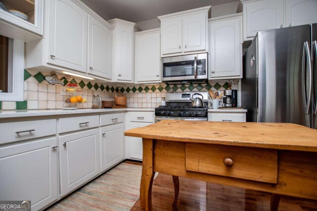 kitchen featuring tasteful backsplash, white cabinets, light wood-style floors, wood counters, and stainless steel appliances