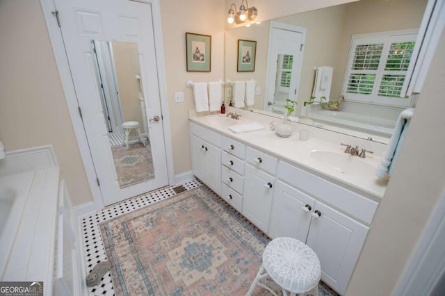 bathroom featuring a sink, an inviting chandelier, a garden tub, and double vanity
