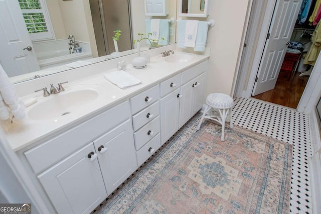 full bath with a sink, a bath, and double vanity