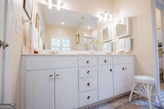 full bathroom with double vanity, a sink, toilet, and a shower stall