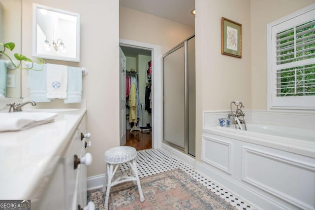 bathroom with vanity, a walk in closet, a garden tub, and a stall shower
