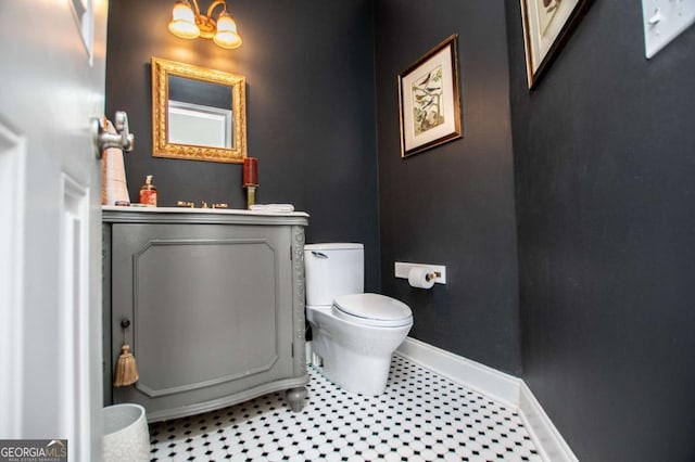 half bathroom featuring baseboards, toilet, and a chandelier