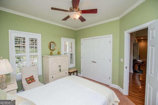 bedroom with crown molding, a closet, wood finished floors, baseboards, and a ceiling fan