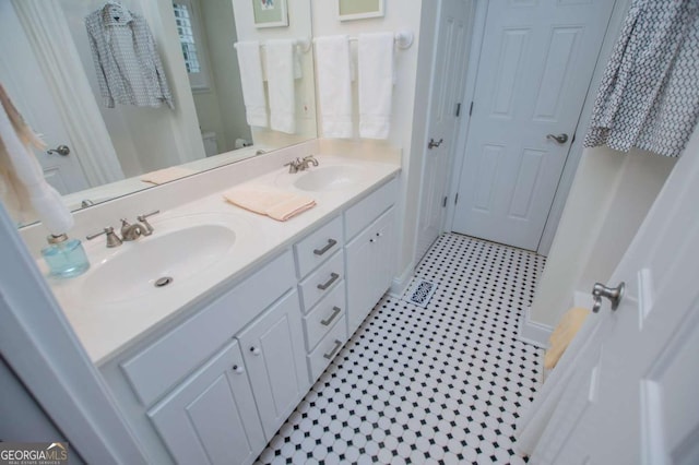 bathroom featuring double vanity, a sink, and toilet