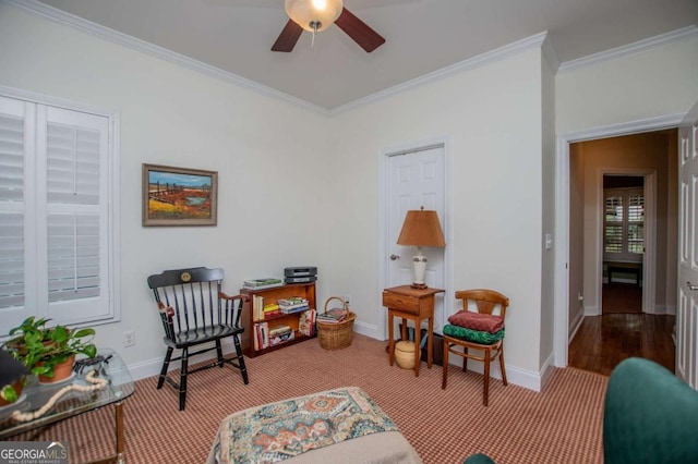 sitting room with crown molding, carpet, baseboards, and ceiling fan