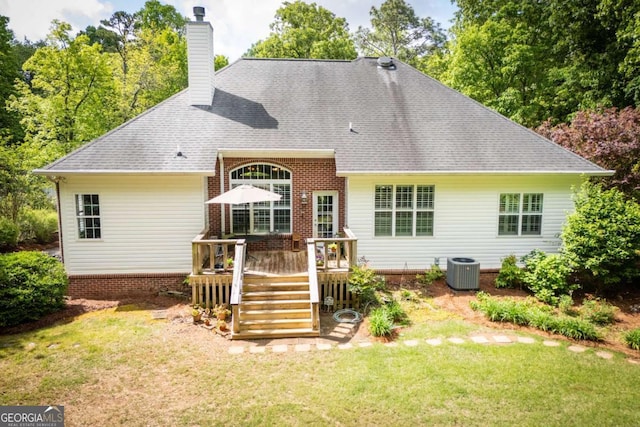 rear view of house featuring a deck, a chimney, a shingled roof, central air condition unit, and a yard