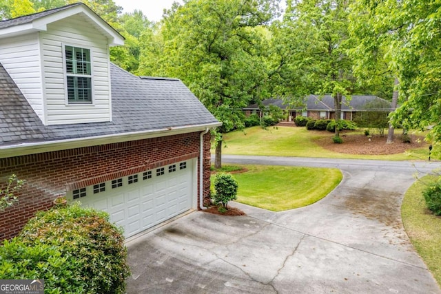 view of property exterior with roof with shingles, a yard, driveway, and brick siding