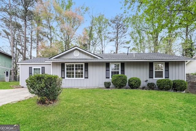 ranch-style house with fence, board and batten siding, a front lawn, and roof with shingles