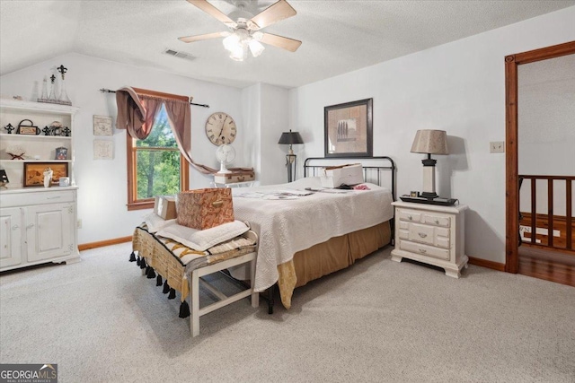 bedroom featuring visible vents, light carpet, a textured ceiling, and lofted ceiling