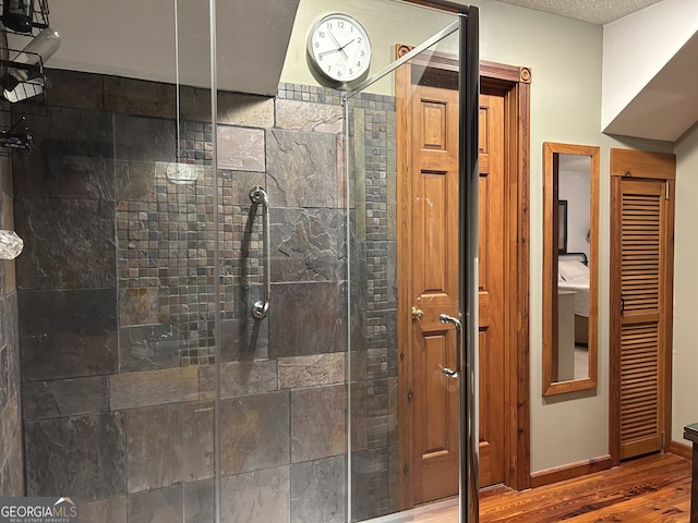 bathroom with a stall shower, wood finished floors, and baseboards