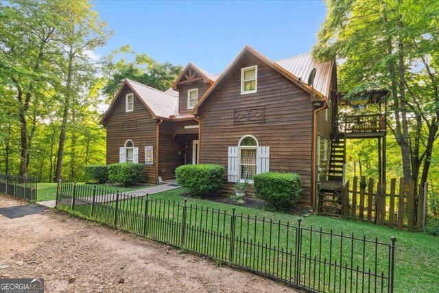 view of front of property with a fenced front yard, a front yard, metal roof, and stairs