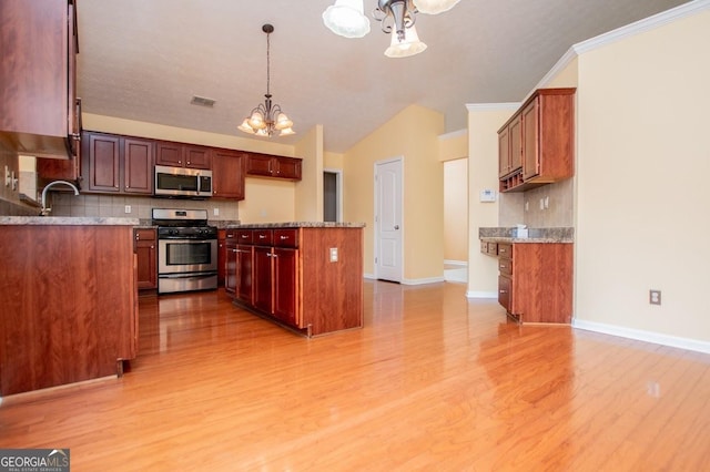 kitchen featuring appliances with stainless steel finishes, tasteful backsplash, a notable chandelier, and vaulted ceiling