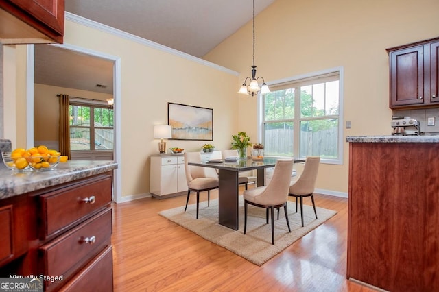 dining space with light wood finished floors, a notable chandelier, vaulted ceiling, baseboards, and ornamental molding