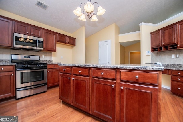 kitchen with an inviting chandelier, stainless steel appliances, tasteful backsplash, visible vents, and lofted ceiling