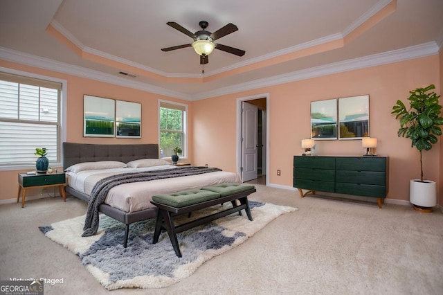 bedroom featuring ornamental molding, light colored carpet, and a tray ceiling