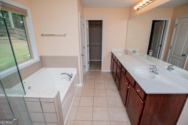 bathroom with tile patterned floors, a garden tub, baseboards, and a sink