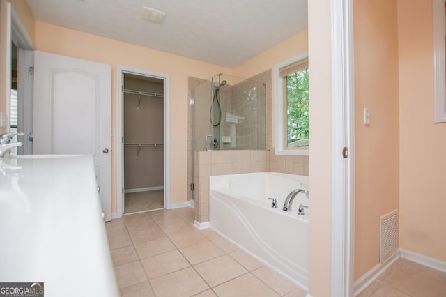 full bath featuring visible vents, tile patterned floors, a shower stall, a bath, and a spacious closet