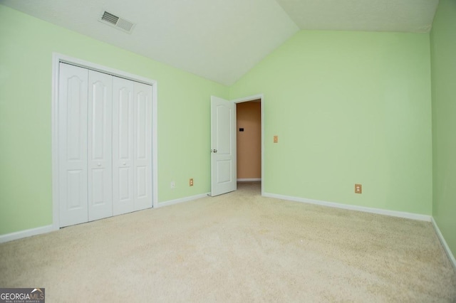 unfurnished bedroom with lofted ceiling, visible vents, baseboards, and carpet floors