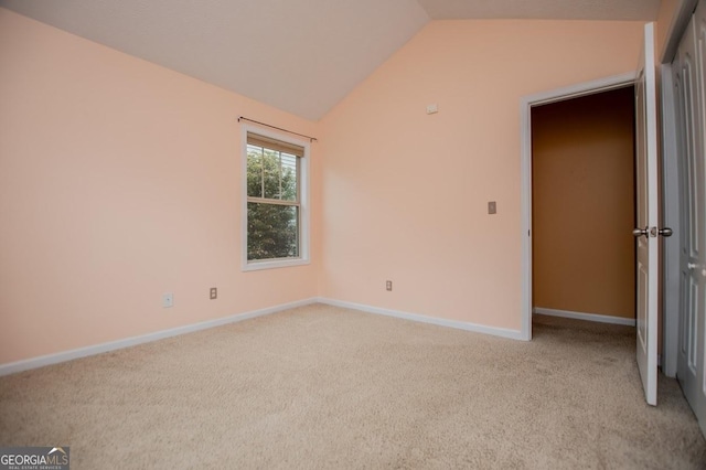 unfurnished bedroom featuring baseboards, light carpet, and lofted ceiling