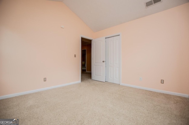 unfurnished room featuring baseboards, visible vents, light colored carpet, and vaulted ceiling