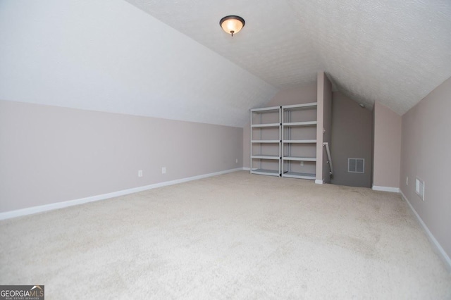additional living space featuring baseboards, visible vents, lofted ceiling, and carpet