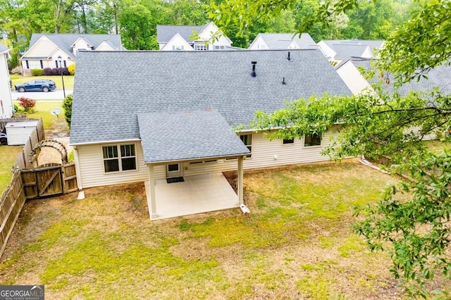 rear view of property with fence, a patio, a gate, a shingled roof, and a lawn