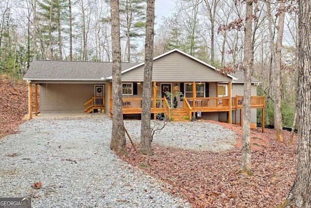 view of front of house with covered porch, a shingled roof, an attached carport, and driveway