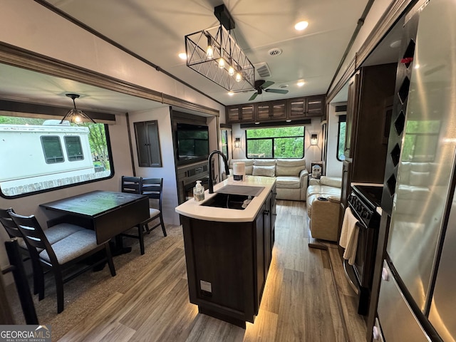 kitchen with a sink, light countertops, freestanding refrigerator, black range with gas stovetop, and open floor plan