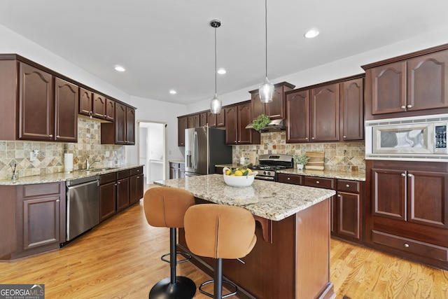 8275 Majors Ridge Way, Cumming, GA 30041 - kitchen with appliances with stainless steel finishes, a sink, light wood-style floors, a center island, and backsplash