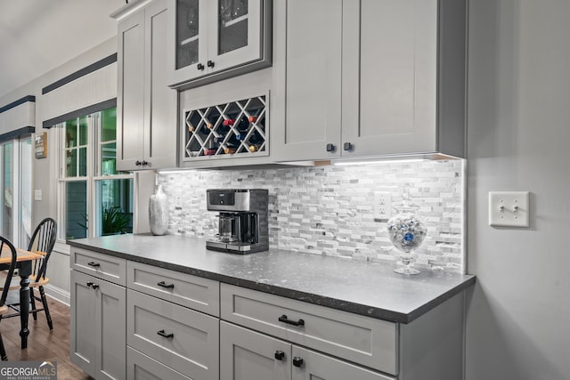 kitchen featuring glass insert cabinets, dark wood-style flooring, baseboards, and tasteful backsplash
