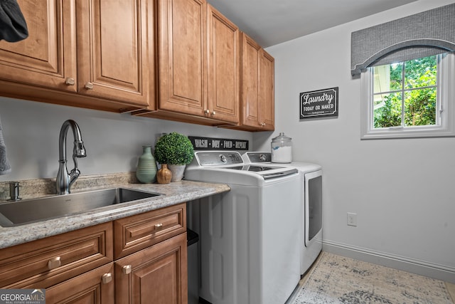 washroom featuring baseboards, washer and dryer, cabinet space, and a sink