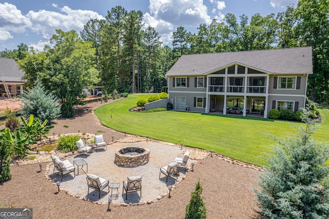 rear view of property featuring a patio, a sunroom, an outdoor fire pit, a yard, and roof with shingles