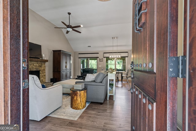 living room with visible vents, wood finished floors, a ceiling fan, high vaulted ceiling, and a stone fireplace