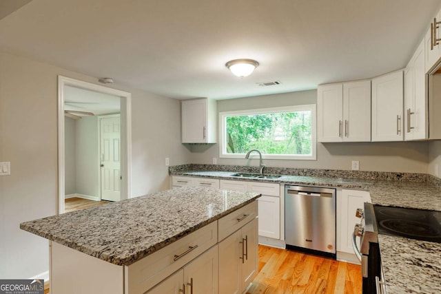 kitchen featuring a sink, appliances with stainless steel finishes, visible vents, light wood-type flooring, and light stone countertops