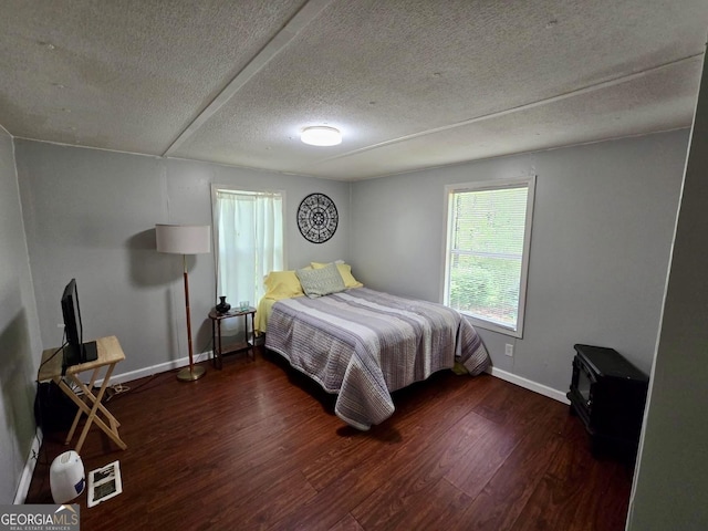 bedroom with a textured ceiling, baseboards, visible vents, and wood finished floors