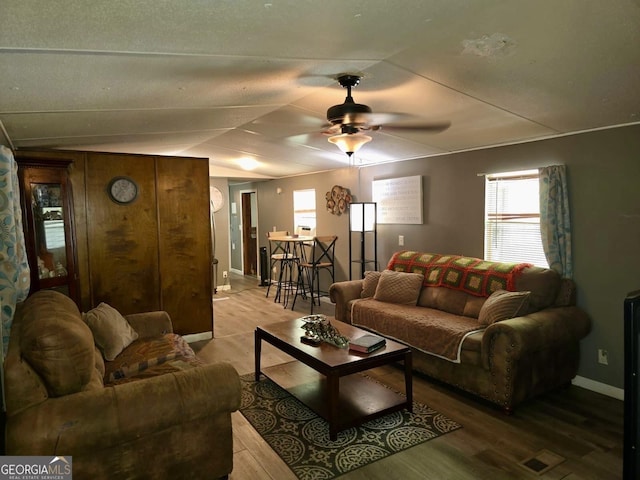 living area featuring a ceiling fan, a wealth of natural light, and wood finished floors