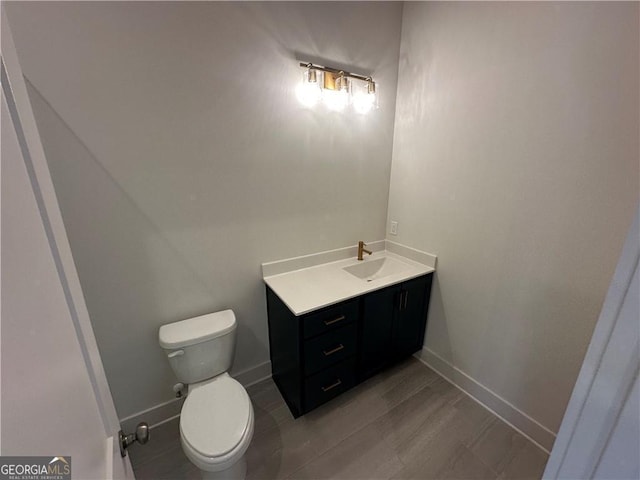 half bath with toilet, vanity, and baseboards