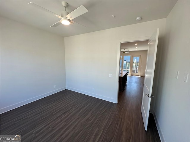 empty room featuring dark wood-style floors, ceiling fan, and baseboards