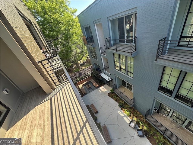 view of property exterior featuring a patio, a balcony, and brick siding