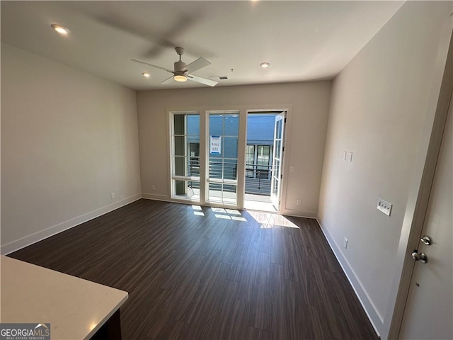 spare room featuring baseboards, a ceiling fan, and dark wood-style floors