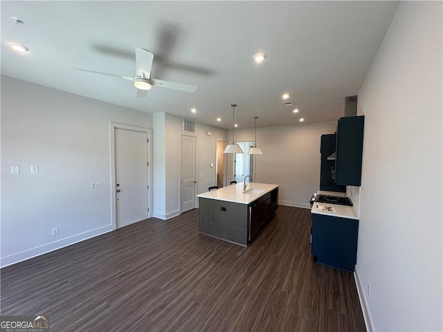 kitchen featuring light countertops, a sink, baseboards, visible vents, and dark wood-style floors