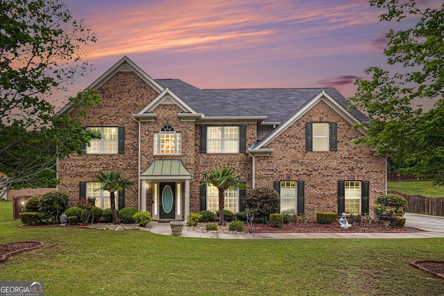 colonial house with a yard and brick siding