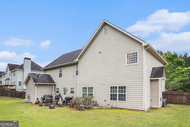 back of house with a lawn, central AC unit, and fence
