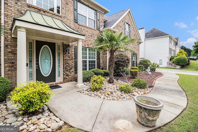 doorway to property featuring a standing seam roof and brick siding