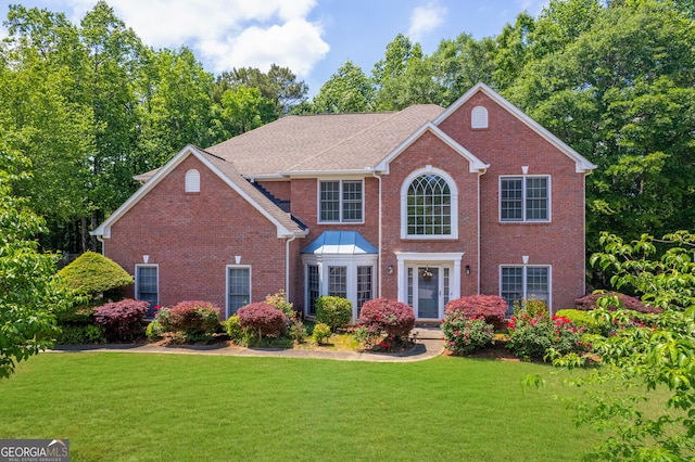 colonial home with brick siding and a front lawn